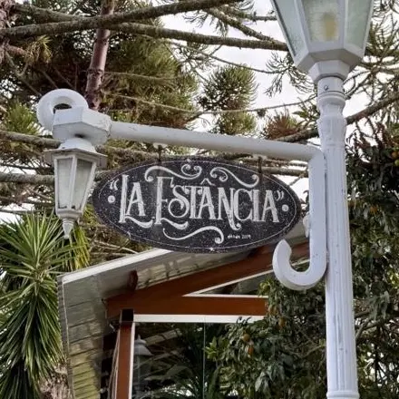 Placa “La Estância” no poste branco da entrada do sítio